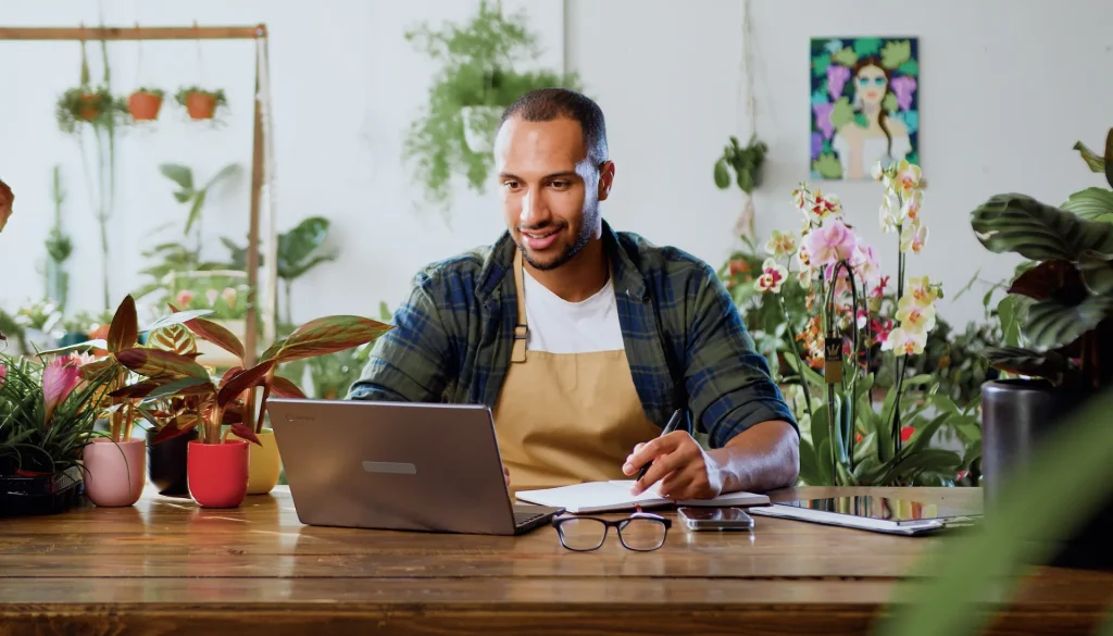 Guy in a flowershop using his laptop